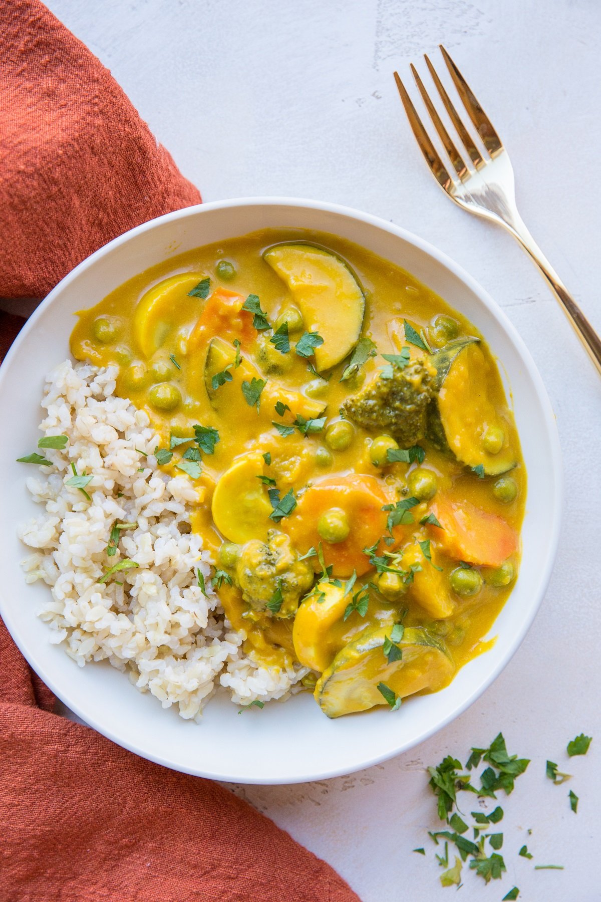 Vegan Pumpkin Curry in a white bowl with rice and a red napkin to the side.