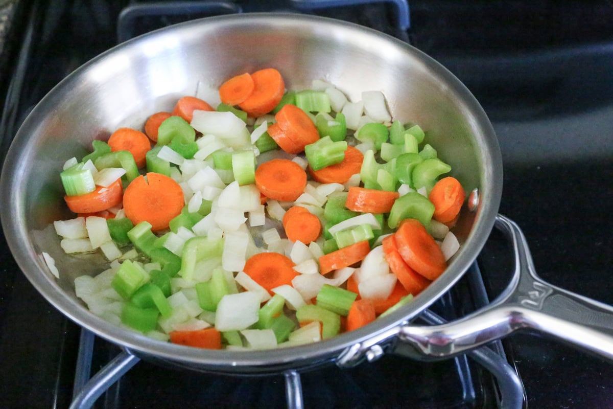 Skillet with onion, celery and carrots cooking.