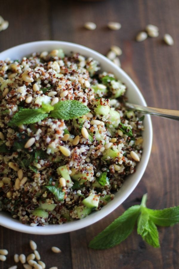 large white bowl full of tri color quinoa salad sprinkled with pine nuts and fresh mint.