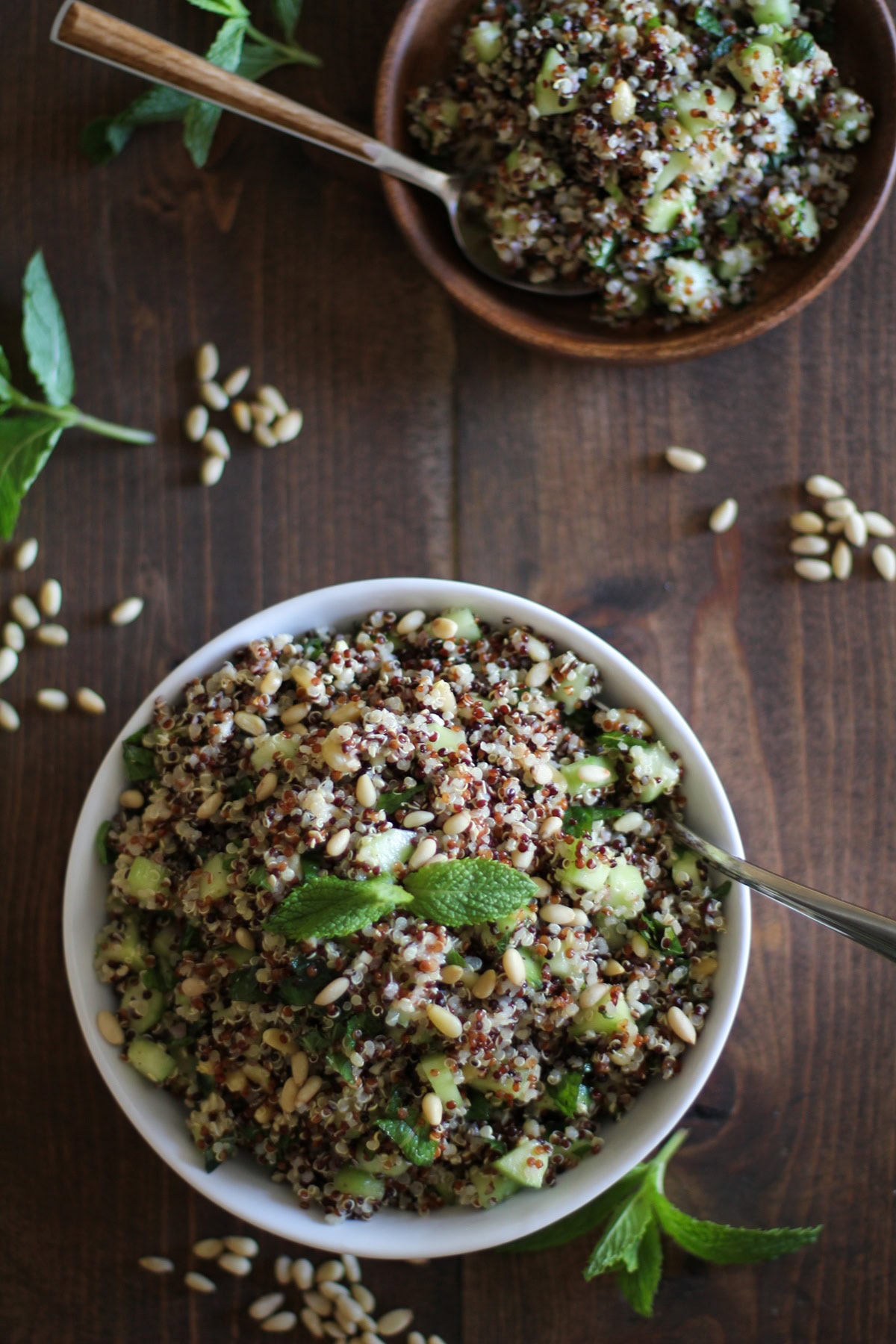 Big white bowl of quinoa salad with cucumber, pine nuts and mint lime dressing.