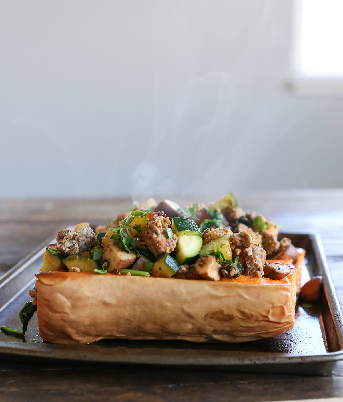 steam rising above stuffed butternut squash with turkey and zucchini, fresh out of the oven and still hot.