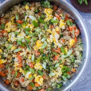 Turnip fried rice in a stainless steel skillet with a napkin and a bowl of sesame seeds to the side.