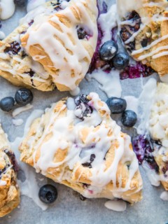 Baking sheet of gluten-free blueberry scones drizzled with glaze.