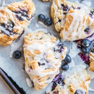 Sheet pan lined with parchment paper with dairy-free blueberry scones.