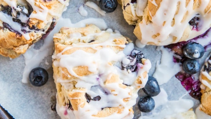 Sheet pan lined with parchment paper with dairy-free blueberry scones.