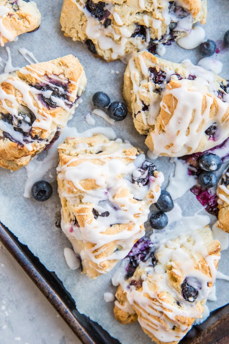 Sheet pan lined with parchment paper with dairy-free blueberry scones.