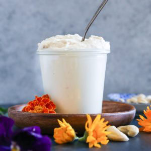 jar full of vegan cream cheese frosting with a spoon inside, ready to use to frost cakes.