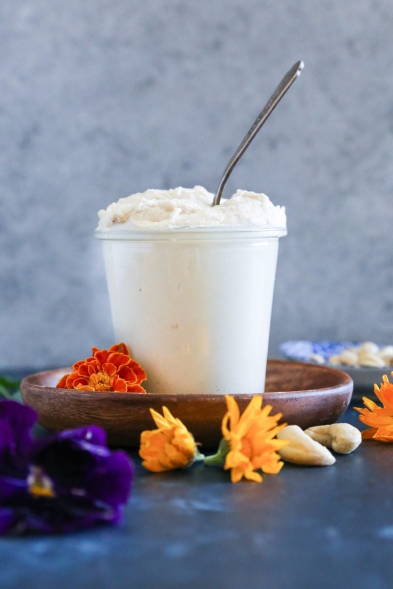 jar full of vegan cream cheese frosting with a spoon inside, ready to use to frost cakes.