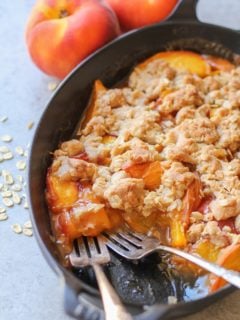 Gluten-Free Vegan Peach Cobbler in a cast iron casserole dish with two forks, ready to eat.