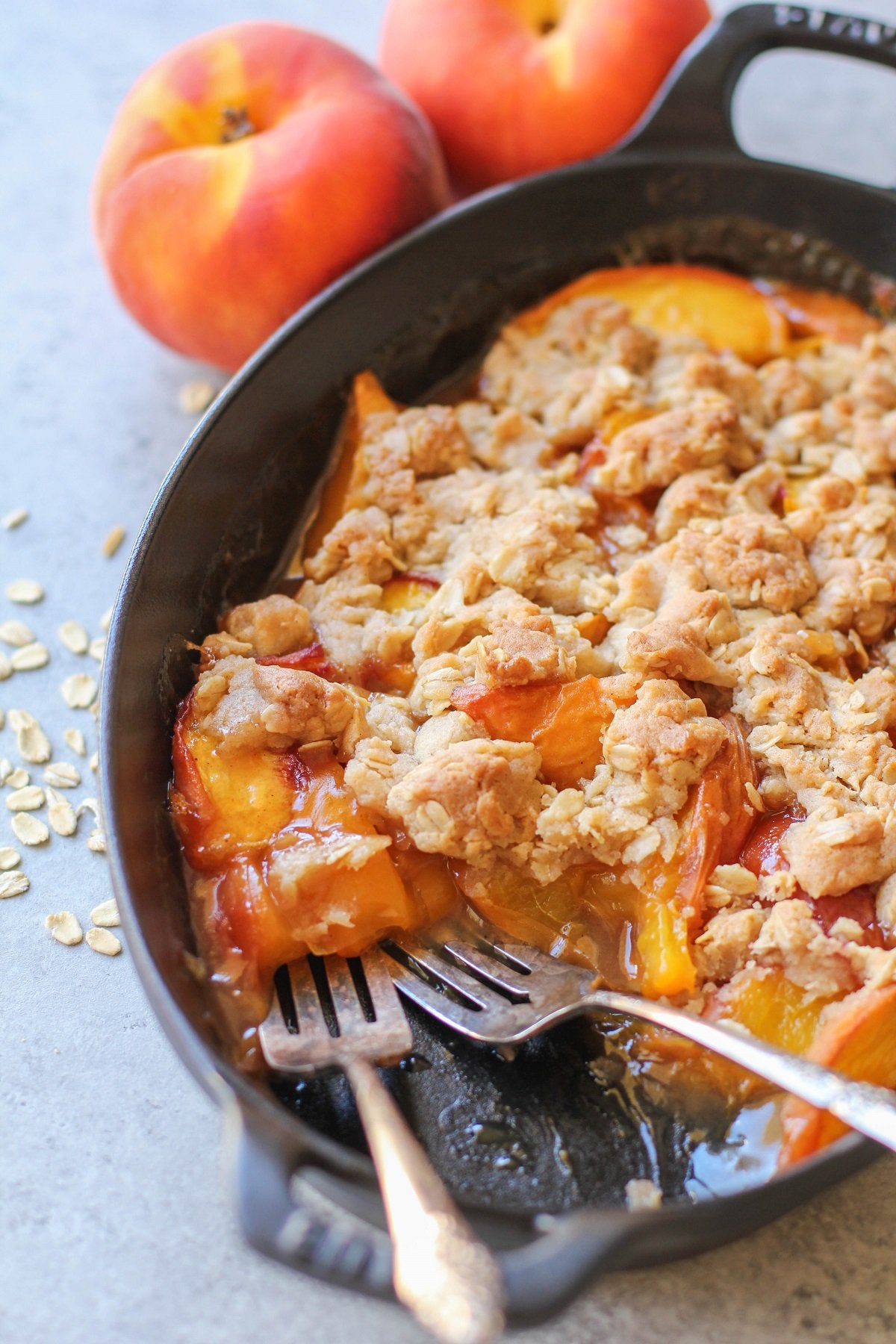 Gluten-Free Vegan Peach Cobbler in a cast iron casserole dish with two forks, ready to eat.