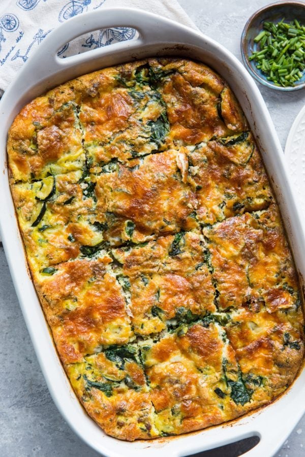 Large white casserole dish full of egg casserole with sausage and spinach, ready to serve.