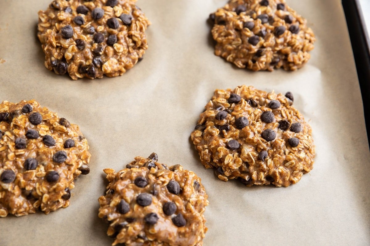 Mounds of cookie dough in cookie shapes on a parchment lined cookie sheet.