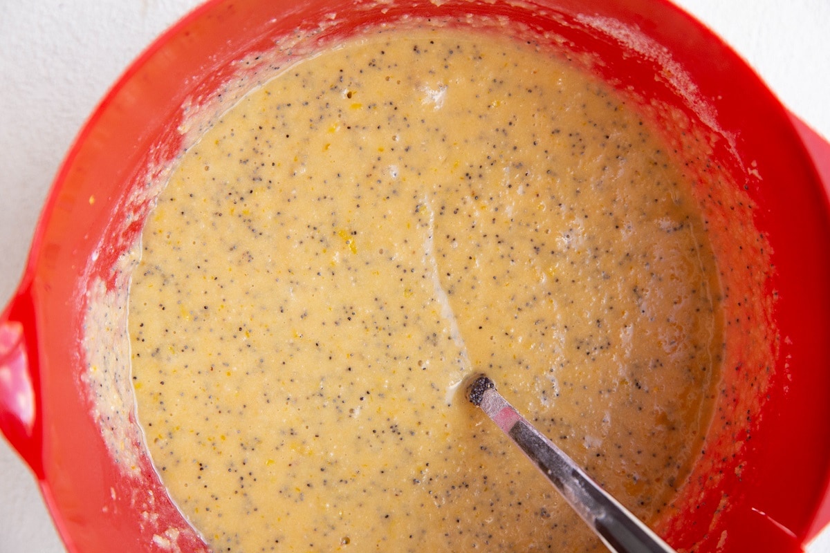 Lemon poppy seed loaf batter in a red mixing bowl, ready to be baked.