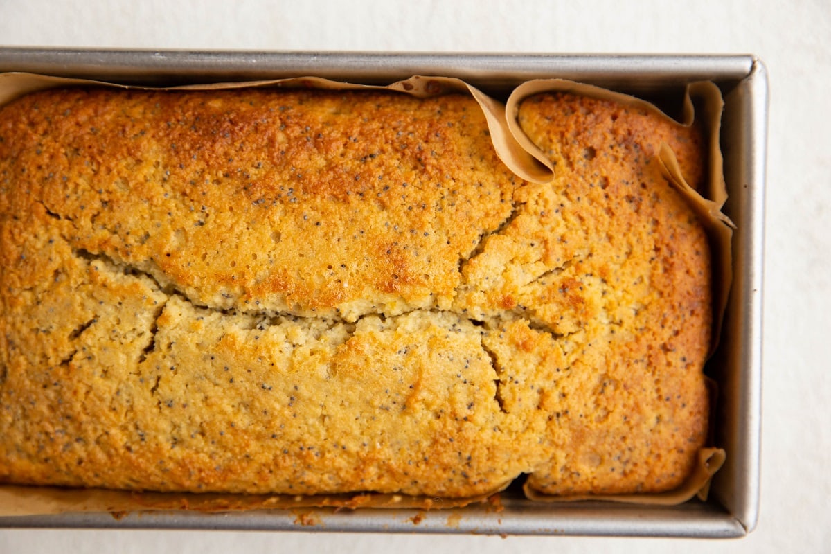 Loaf of lemon poppy seed bread in a bread pan, fresh out of the oven.