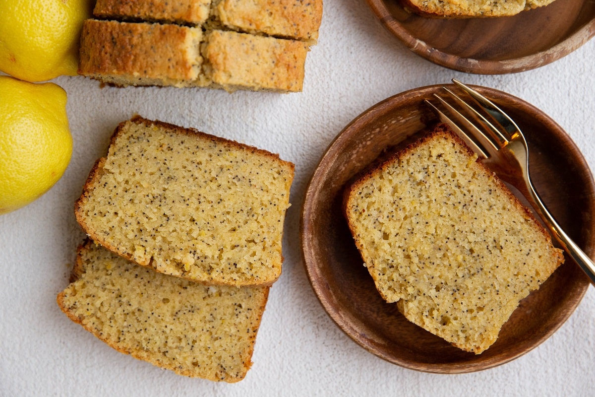 wooden plates with slices of lemon loaf and the rest of the lemon loaf to the side.