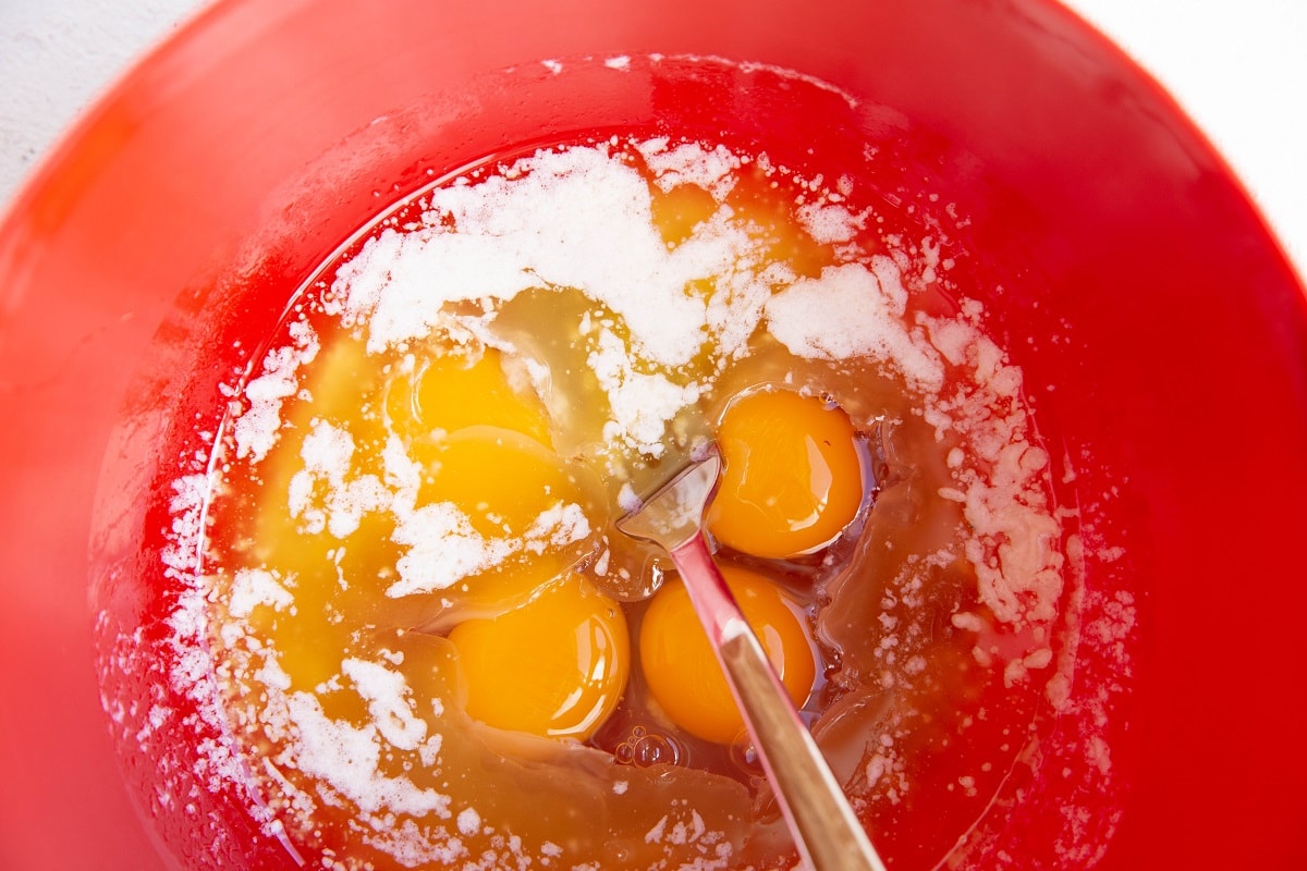 Melted butter and eggs in a mixing bowl to be mixed together for cake.