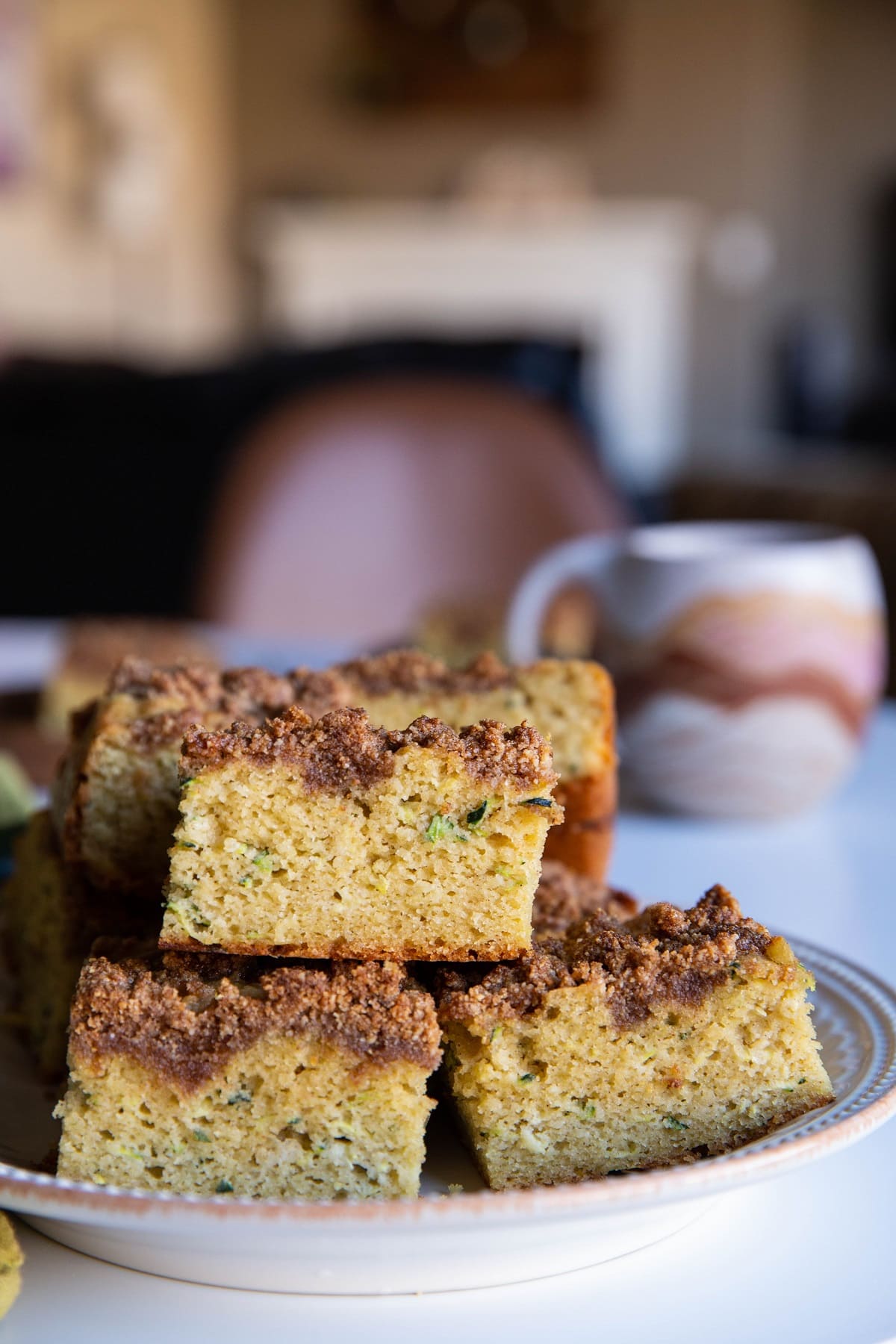 Plate of zucchini cake slices with a mug of tea in the background.
