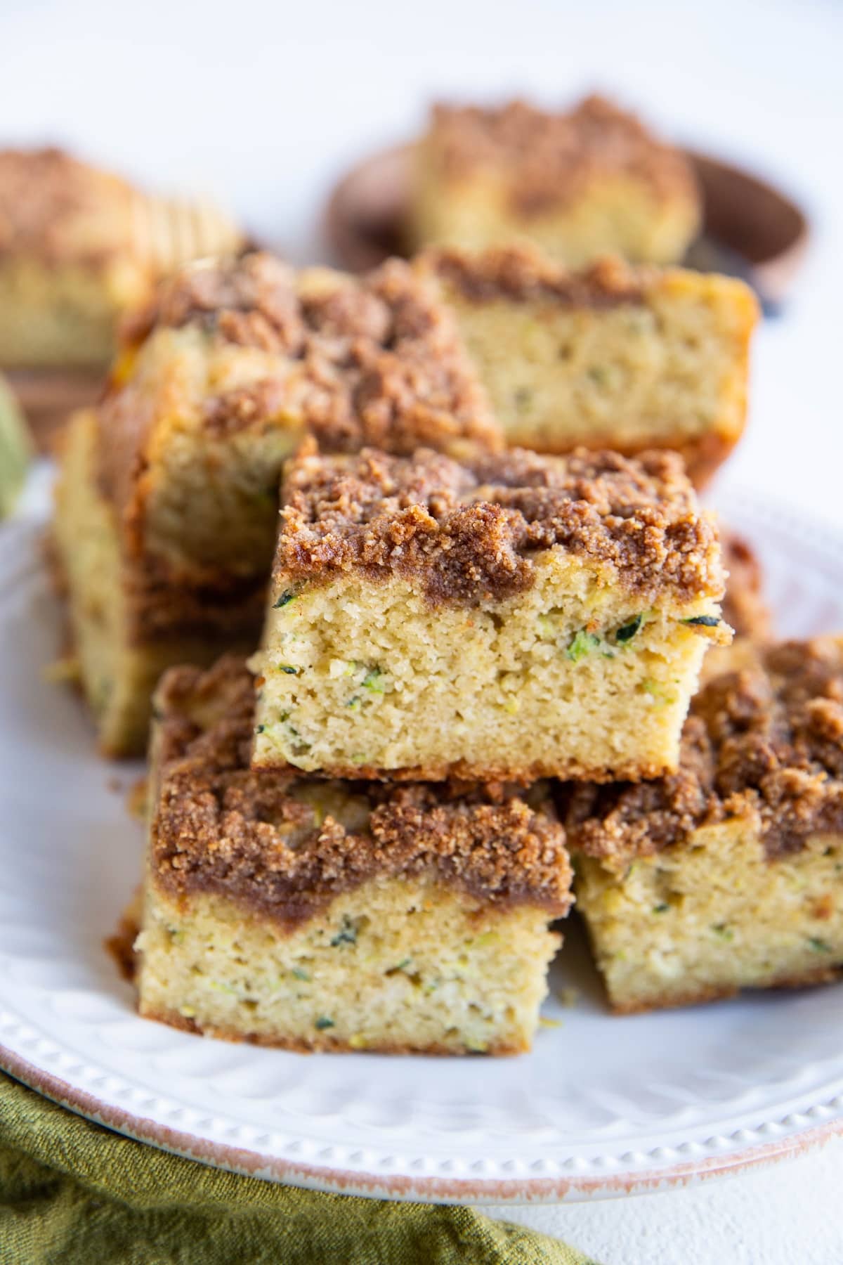Stack of slices of zucchini cake on a white plate, ready to serve.