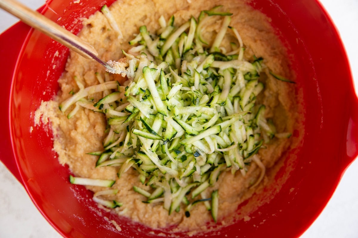 Cake batter in a mixing bowl with grated zucchini ready to be mixed in.