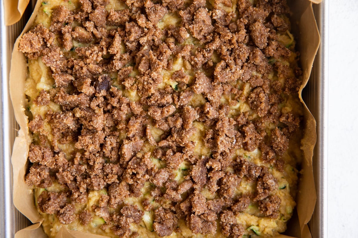 Cake batter with crumble topping in a square pan, ready to go into the oven.