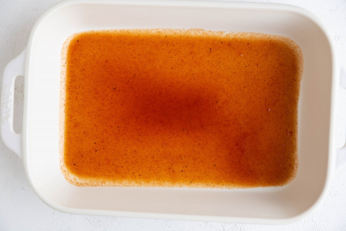 Enchilada sauce at the bottom of the baking dish.