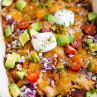 Big white casserole dish of beef enchiladas with corn tortillas.