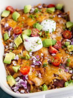 Big white casserole dish of beef enchiladas with corn tortillas.