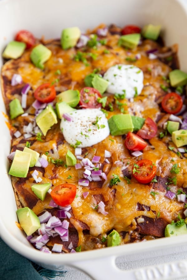 Big white casserole dish of beef enchiladas with corn tortillas.
