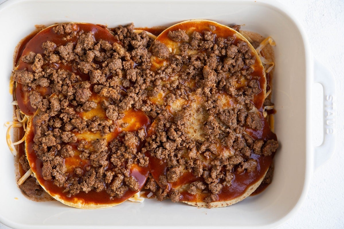 Ground beef on top of enchilada sauce soaked tortillas for the second layer of the casserole.