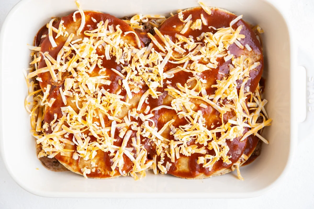 Final layer of tortillas smothered in sauce and grated cheese.