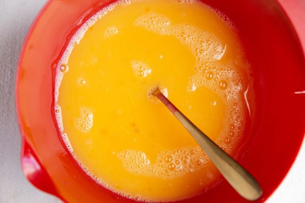 Eggs and egg whites whisked together in a red mixing bowl.