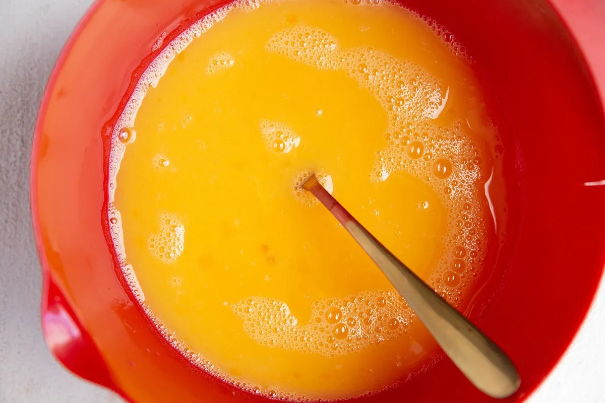 Eggs and egg whites whisked together in a red mixing bowl.