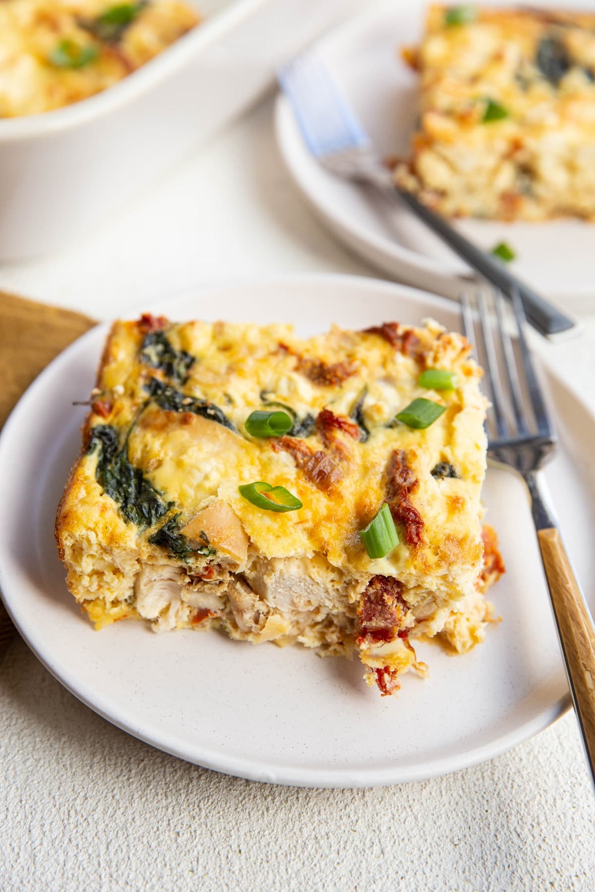 two white plates with slices of egg casserole, ready to eat.