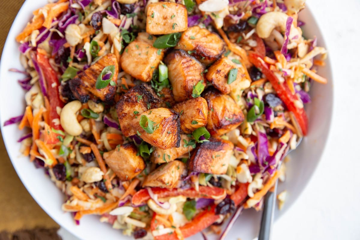 Crispy chunks of cooked salmon on a bed of shredded cabbage and carrot for salad.