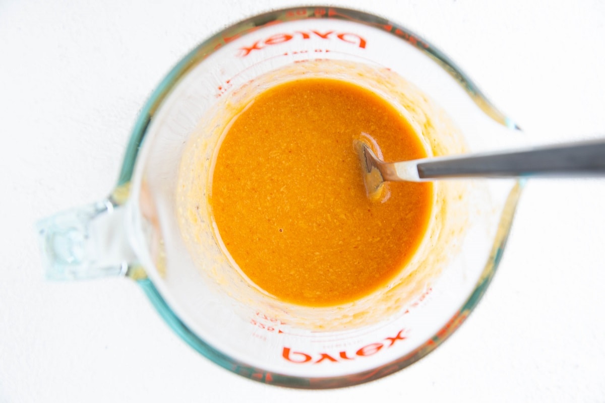 Peanut dressing for salad in a measuring cup.