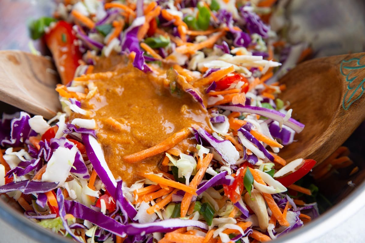 Salad ingredients in a bowl with peanut dressing inside.