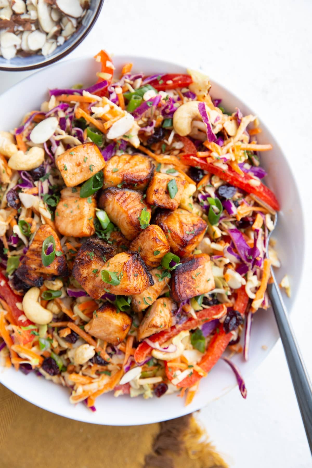 White bowl full of salad fixings with cooked salmon on top.