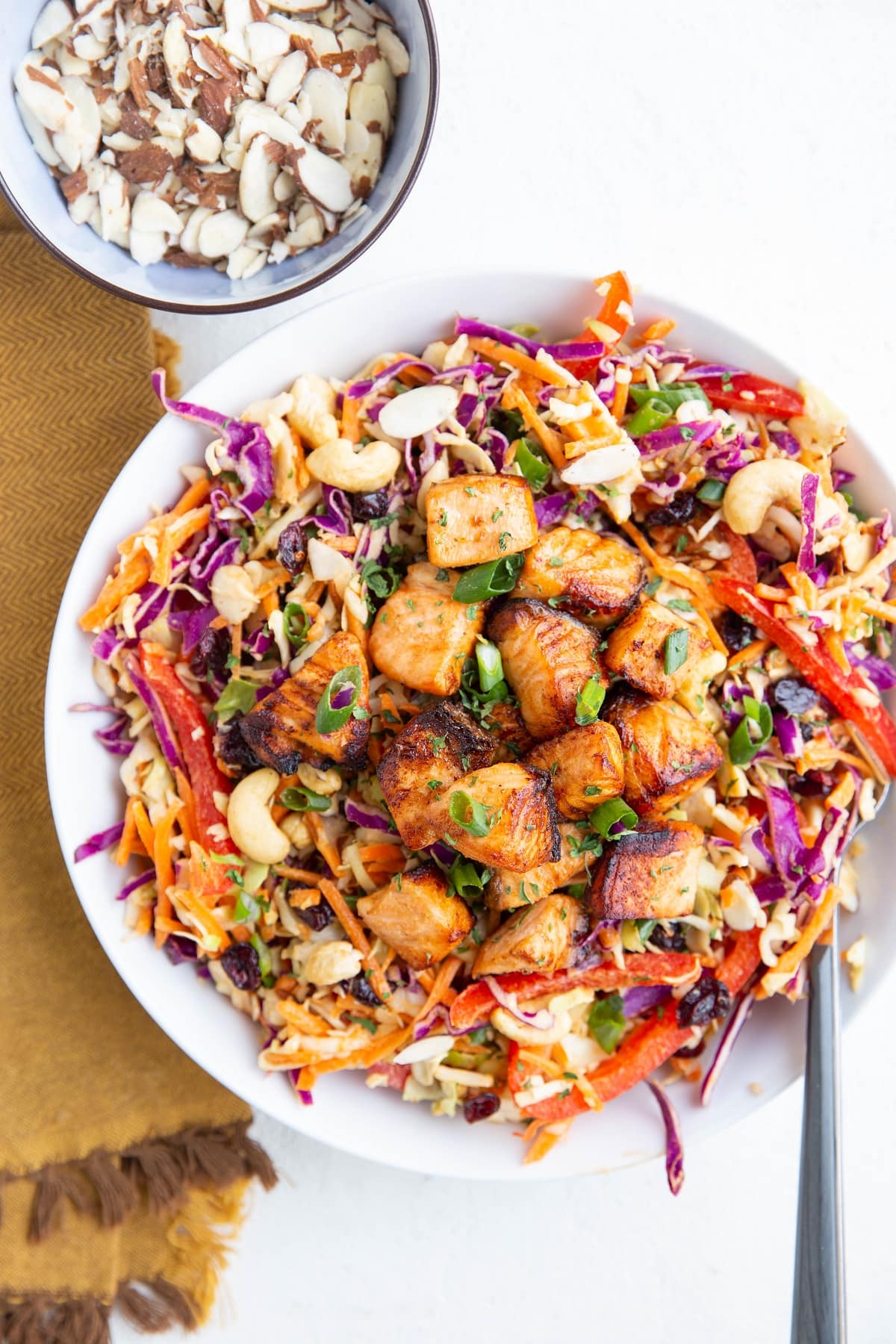 Crispy chunks of cooked salmon on a bed of vegetables for salad.