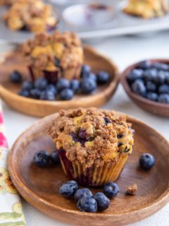 Two blueberry muffins on wooden plates, ready to eat.