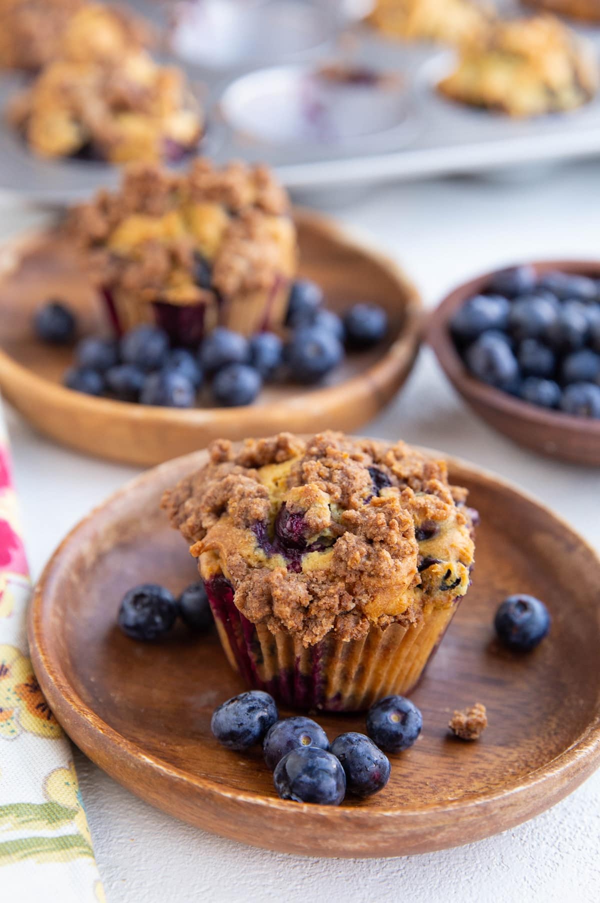 Two blueberry muffins on wooden plates, ready to eat.