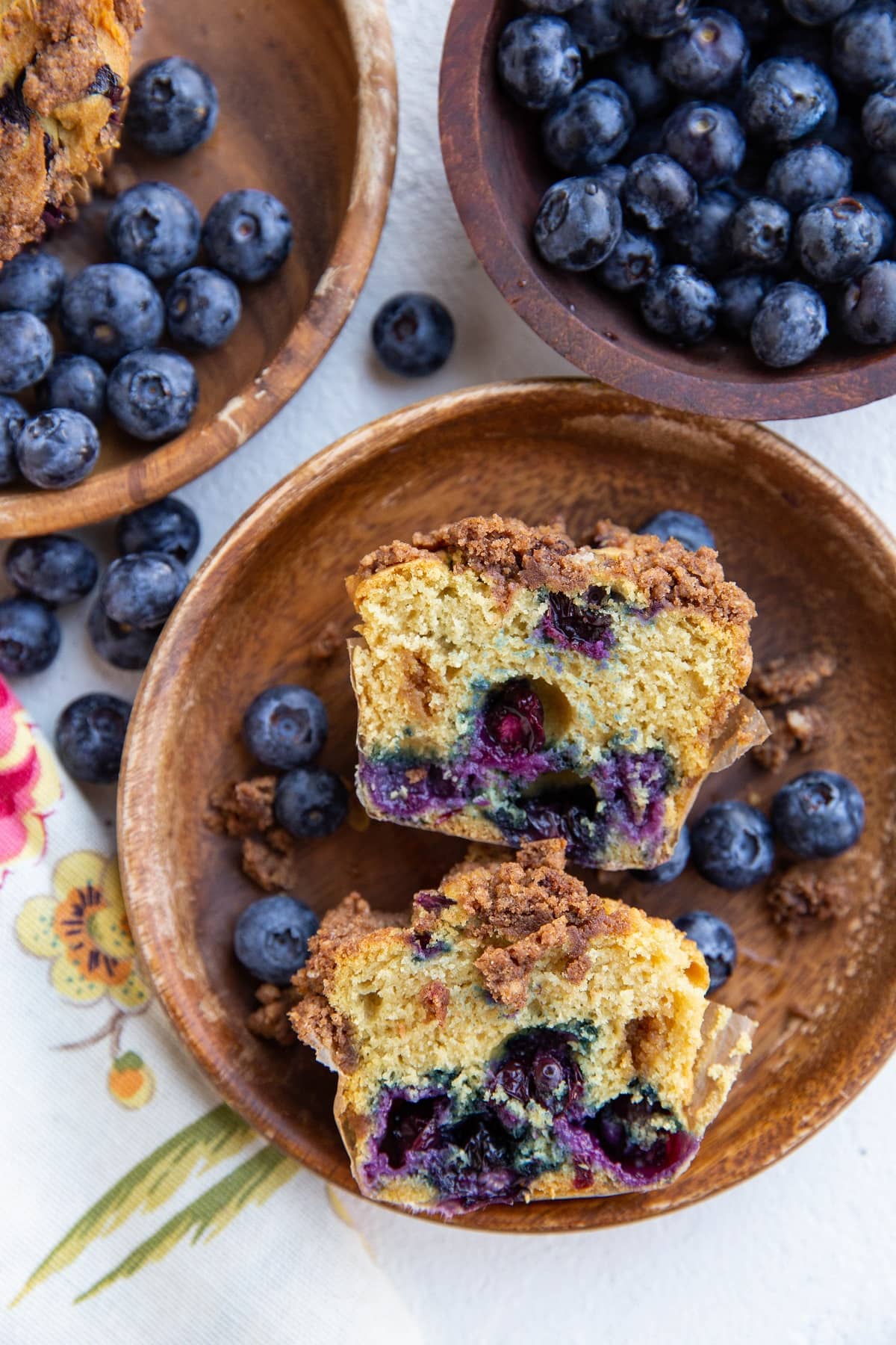 Two plates of blueberry muffins, one that is cut in half to expose the inside.