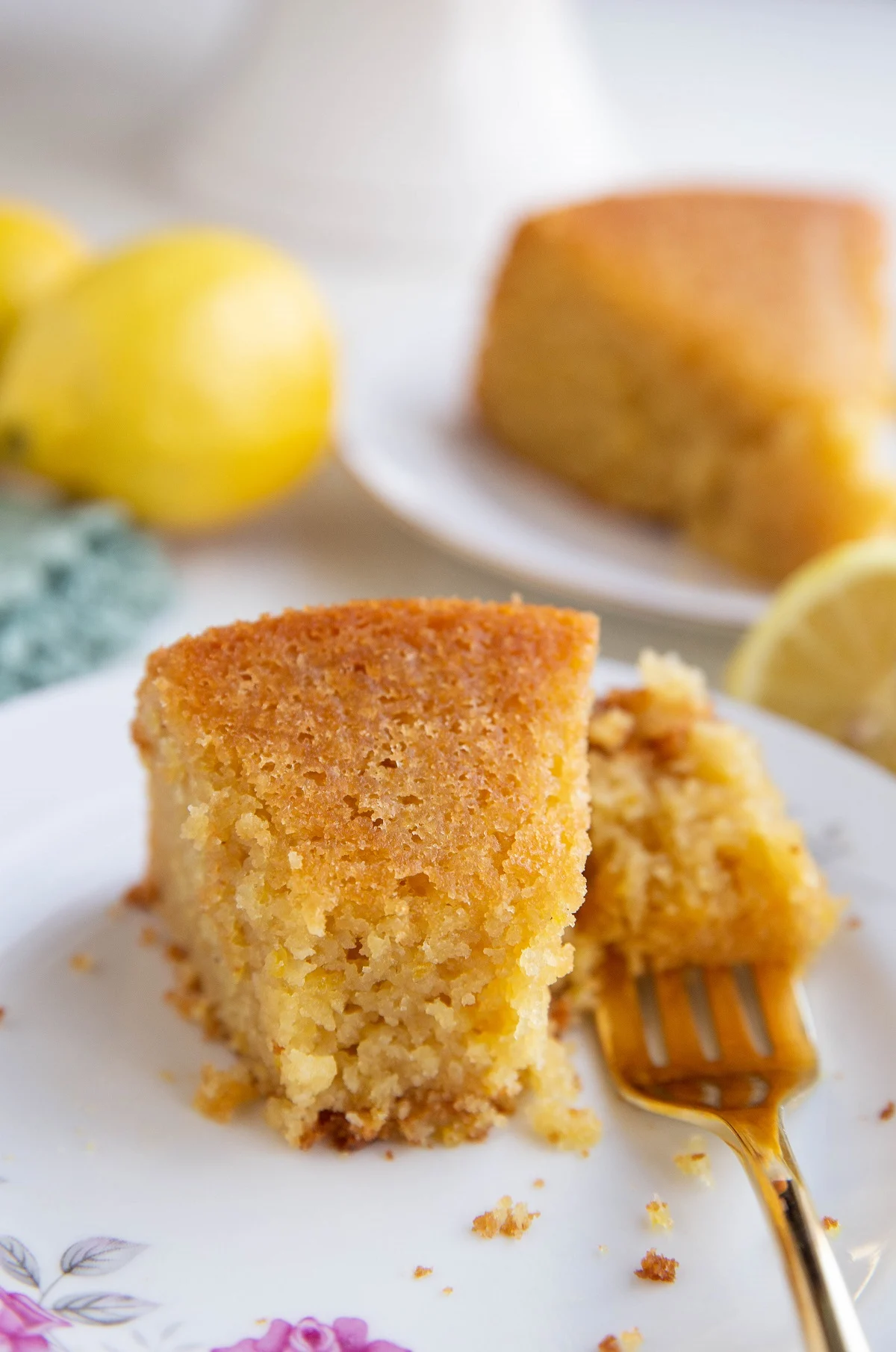 Close up on a slice of lemon cake with a bite taken out so you can see the moist texture.