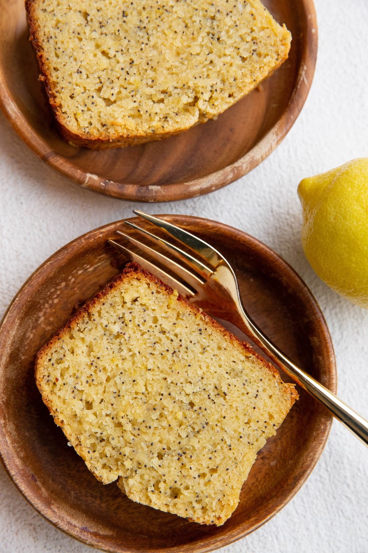 Top down image of two wooden plates with slices of lemon poppy seed bread.