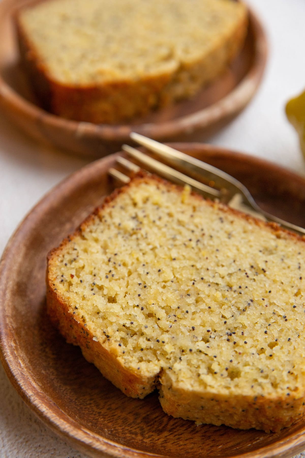 Two thick slices of lemon poppy seed bread on plates with forks.