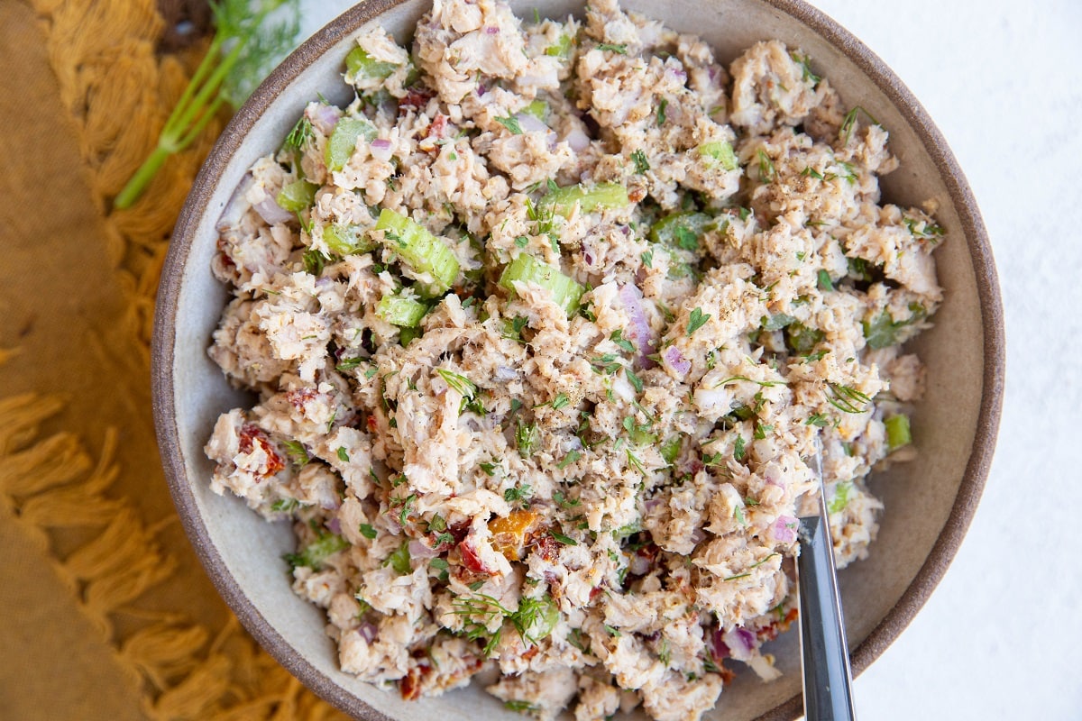 Bowl of freshly made tuna salad with celery, onion, sun-dried tomatoes and more.