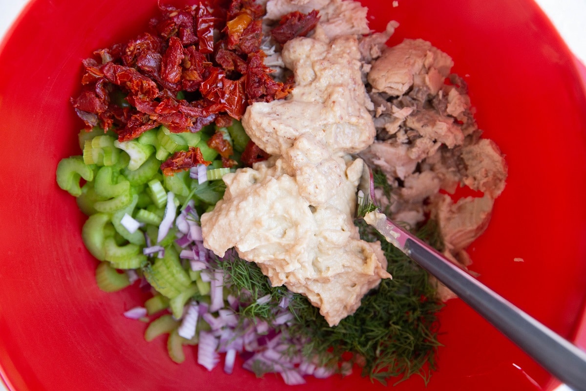 Ingredients for healthy tuna salad in a red mixing bowl.
