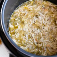 Instant Pot full of shredded chicken in green sauce for tacos or burritos.