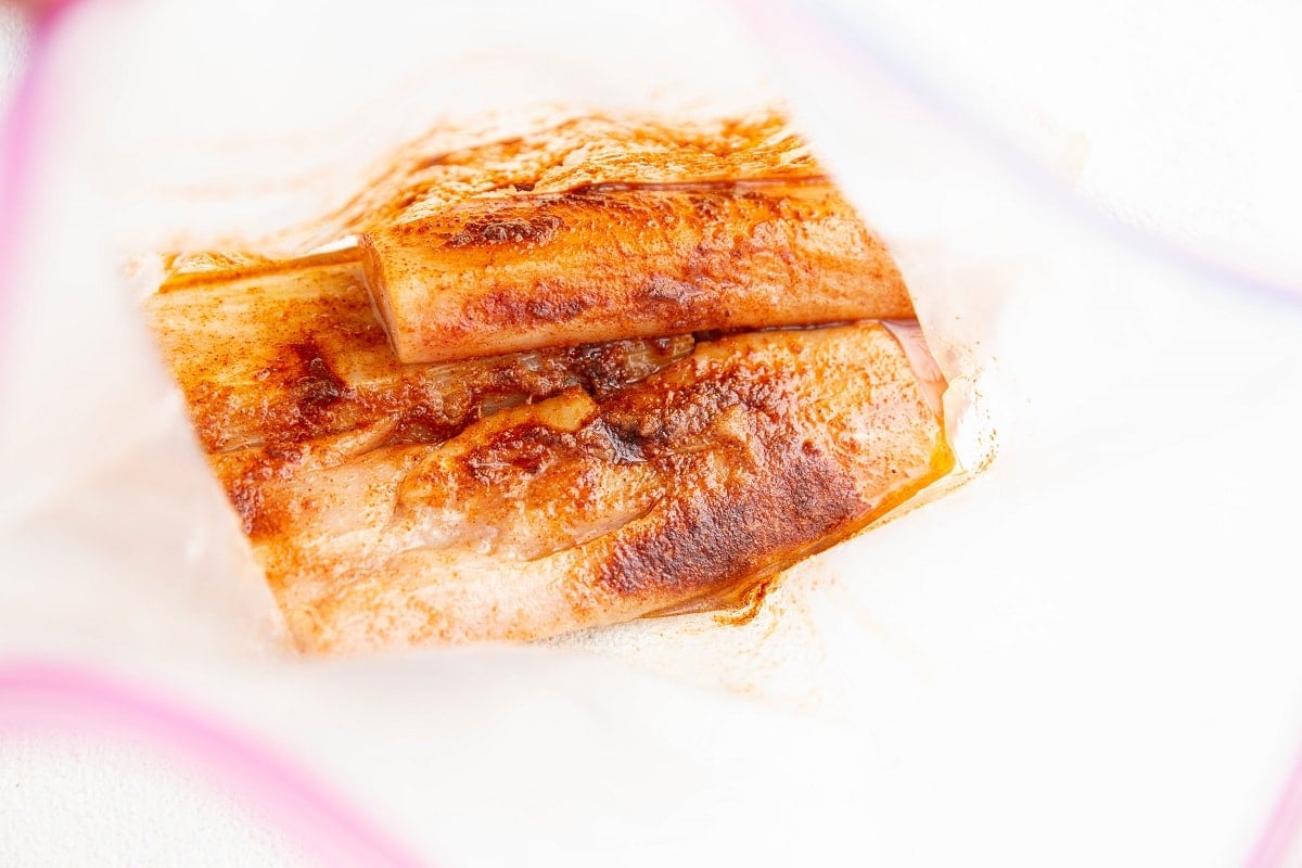 Mahi mahi filets with seasonings and oil in a zip lock bag to be marinated.