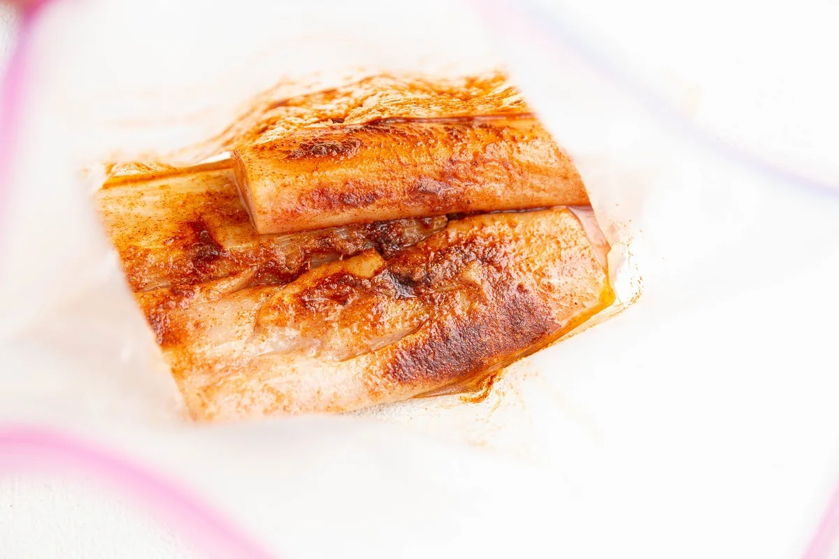 Mahi mahi filets with seasonings and oil in a zip lock bag to be marinated.
