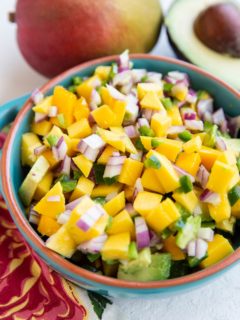 Blue bowl of mango avocado salsa, ready to be enjoyed on top of fish tacos or chicken breasts.